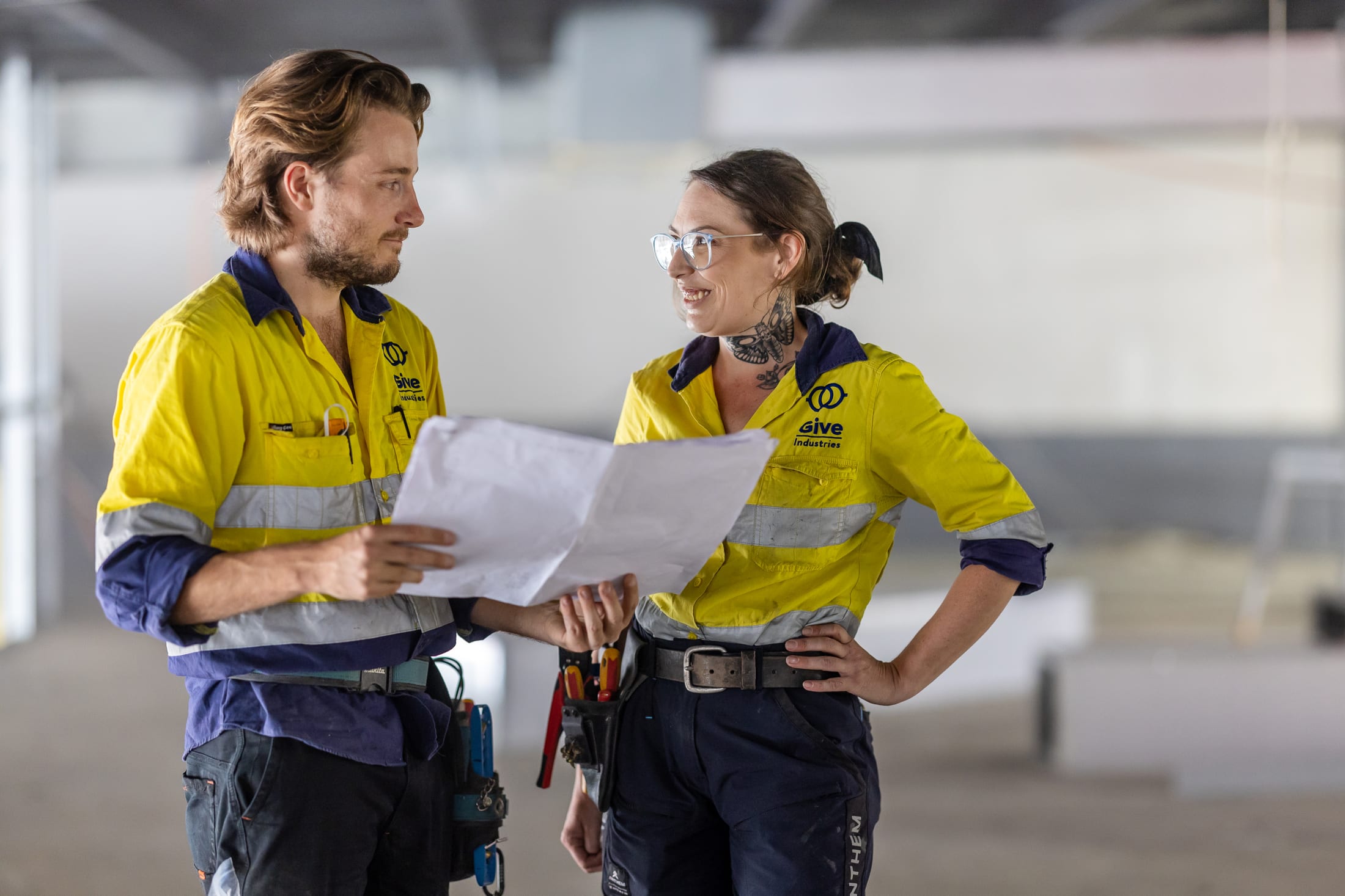 Give Industries electricians discussing plans on a commercial site